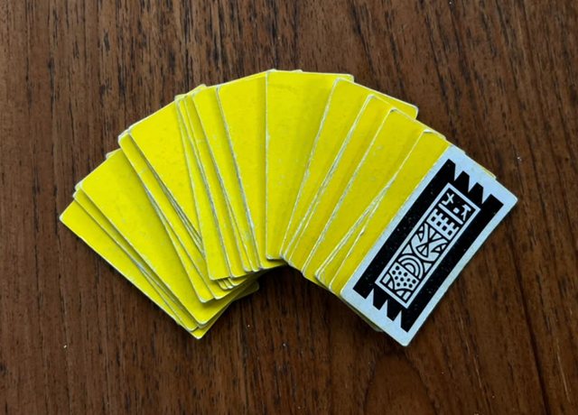A fan of yellow Kartu Ceki cards on a wooden table
